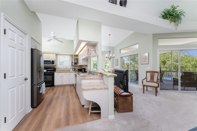 kitchen featuring white cabinetry, black / electric stove, stainless steel fridge, decorative light fixtures, and a breakfast bar