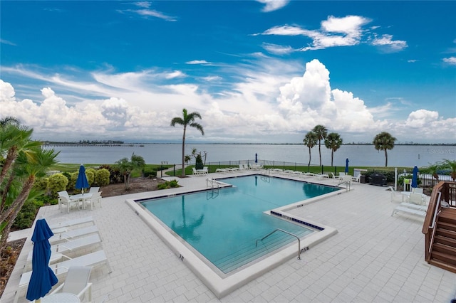 view of pool featuring a water view and a patio