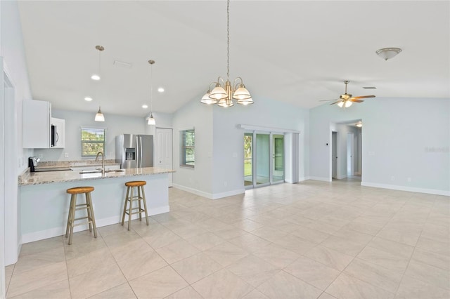 kitchen featuring stainless steel refrigerator with ice dispenser, light stone counters, vaulted ceiling, white cabinets, and range