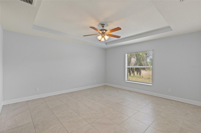 spare room featuring a raised ceiling and light tile patterned floors