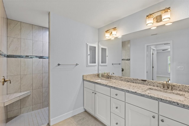 bathroom featuring tile patterned flooring, vanity, and tiled shower