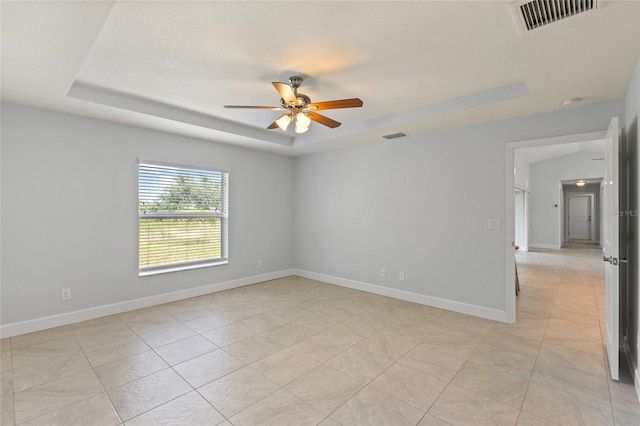 spare room featuring ceiling fan, light tile patterned floors, and a tray ceiling