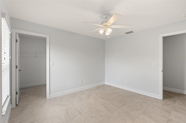 unfurnished bedroom with a walk in closet, ceiling fan, a closet, and light tile patterned floors