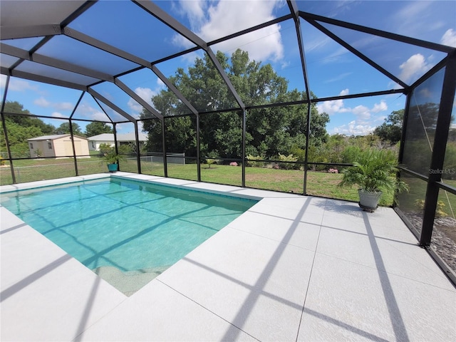 view of pool with glass enclosure, a patio area, and a lawn