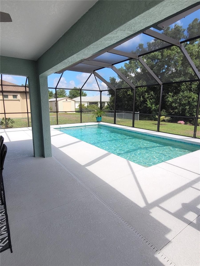 view of swimming pool featuring glass enclosure, a patio area, and a yard