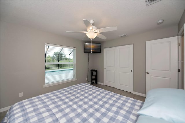 tiled bedroom with ceiling fan and a closet