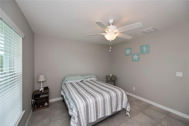 bedroom featuring light tile patterned floors, a textured ceiling, and ceiling fan