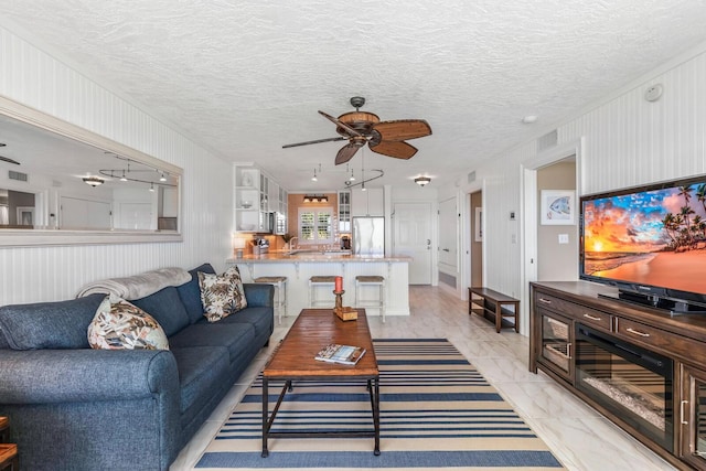 living room with ceiling fan and a textured ceiling