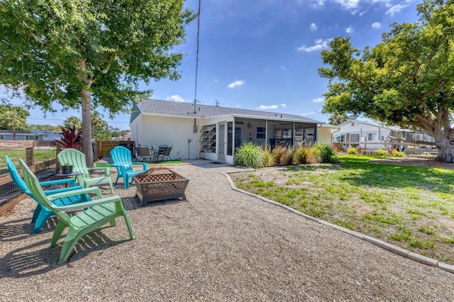 rear view of property featuring a yard, a fire pit, and a sunroom