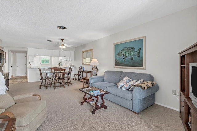 living room featuring ceiling fan, light carpet, and a textured ceiling