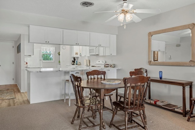 carpeted dining room featuring a textured ceiling and ceiling fan