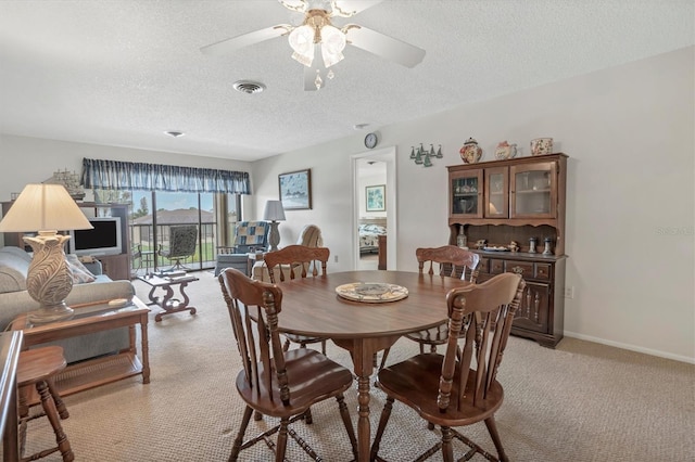 dining room with ceiling fan, light carpet, and a textured ceiling