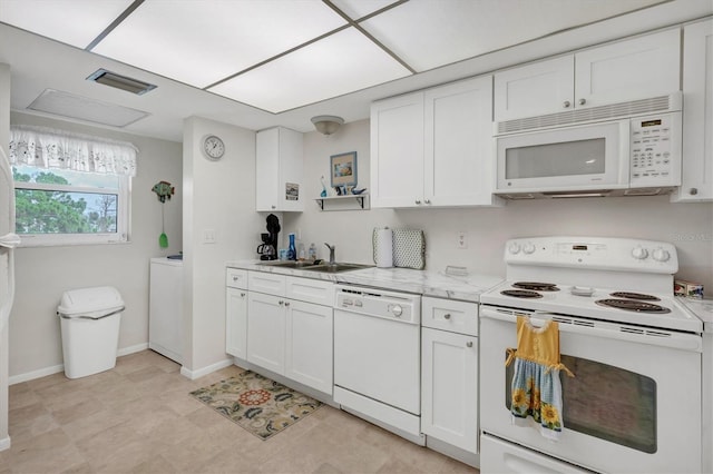 kitchen featuring white cabinetry, sink, white appliances, and washer / dryer