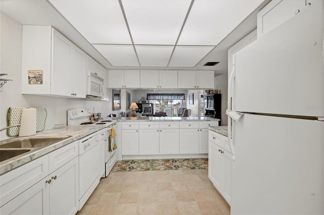 kitchen featuring sink, white cabinets, light stone counters, kitchen peninsula, and white appliances