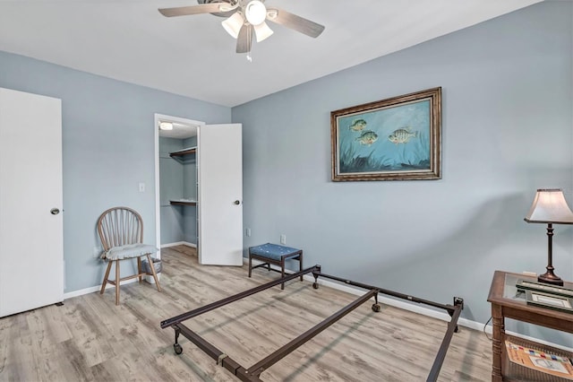 bedroom featuring ceiling fan, a spacious closet, and light hardwood / wood-style flooring