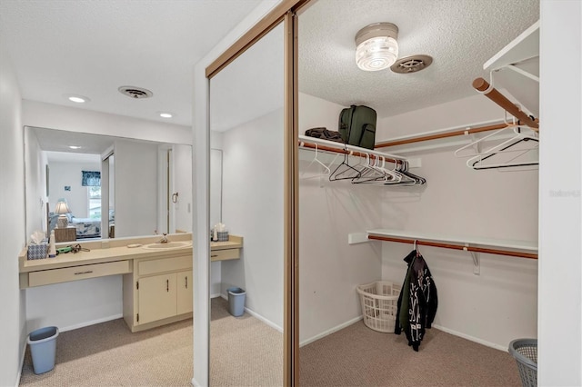 walk in closet featuring sink, built in desk, and light colored carpet