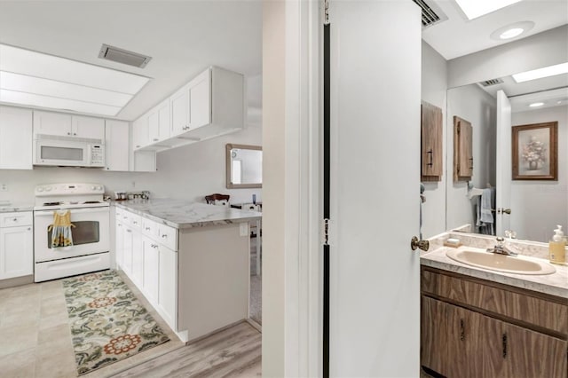 kitchen featuring white cabinetry, sink, and white appliances