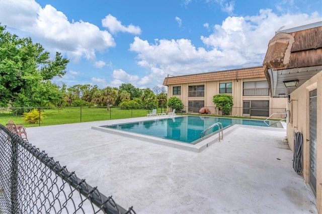 view of swimming pool featuring a patio and a yard