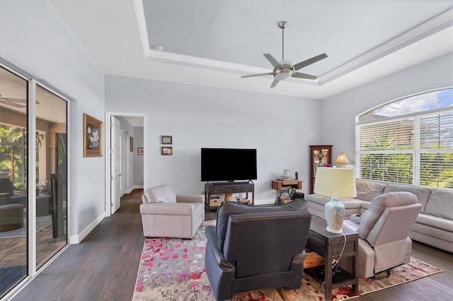 living room featuring dark hardwood / wood-style flooring, ceiling fan, and a raised ceiling