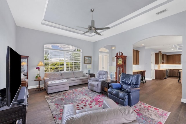 living room featuring ceiling fan, dark hardwood / wood-style flooring, and a raised ceiling