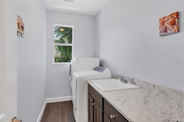 clothes washing area featuring cabinets, sink, dark hardwood / wood-style flooring, and washing machine and dryer