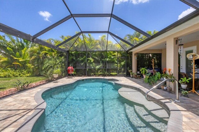 view of pool featuring glass enclosure and a patio area