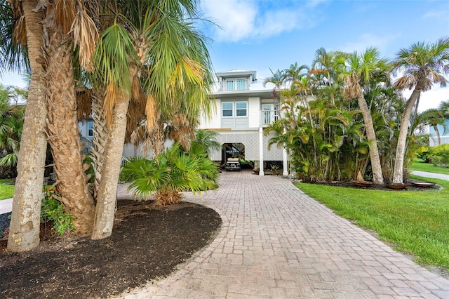 coastal inspired home featuring a front lawn and a carport