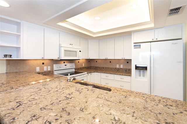 kitchen featuring white cabinets, decorative backsplash, white appliances, and a tray ceiling