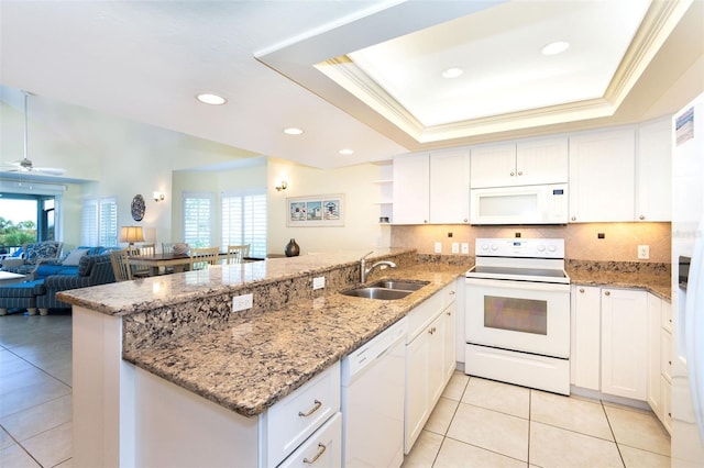 kitchen featuring white appliances, kitchen peninsula, sink, a tray ceiling, and white cabinetry