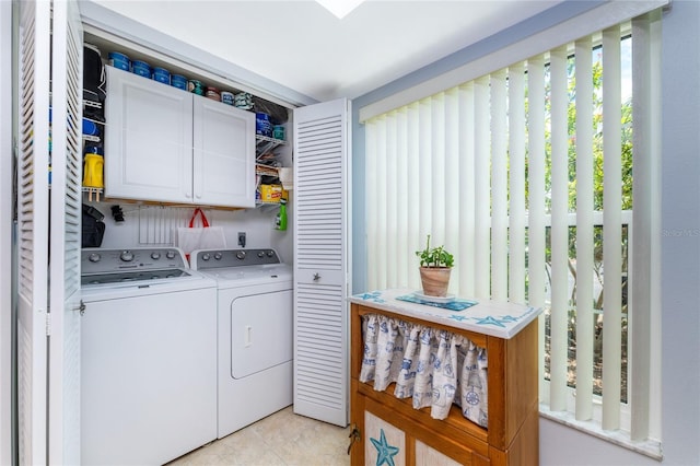 laundry room with washer and clothes dryer, light tile patterned flooring, and cabinets