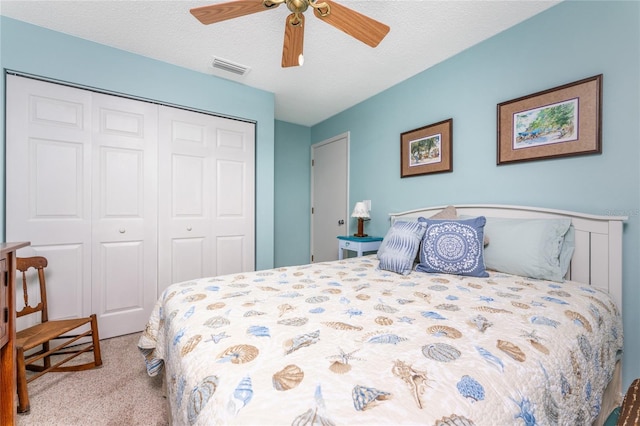 bedroom with a textured ceiling, a closet, ceiling fan, and light colored carpet