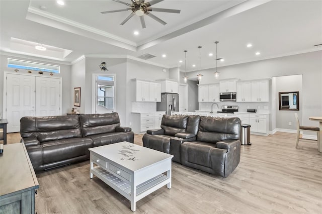 living room featuring a tray ceiling, ceiling fan, sink, and light hardwood / wood-style floors