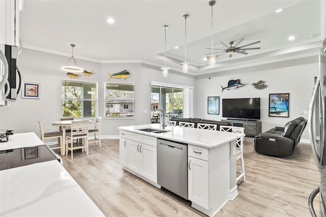 kitchen with white cabinetry, sink, hanging light fixtures, stainless steel appliances, and a kitchen island with sink