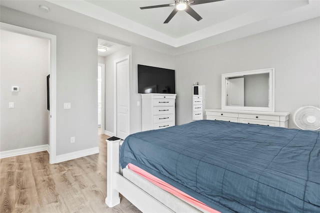 bedroom featuring light hardwood / wood-style floors, a raised ceiling, and ceiling fan