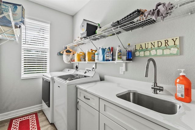 laundry room with washer and clothes dryer, sink, cabinets, and light hardwood / wood-style floors