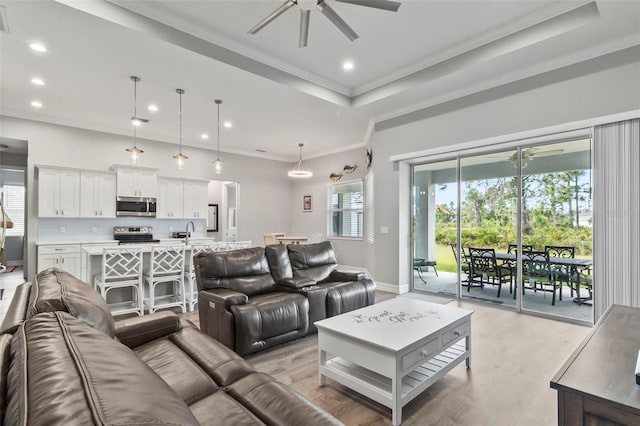 living room with light hardwood / wood-style floors, ceiling fan, ornamental molding, and sink