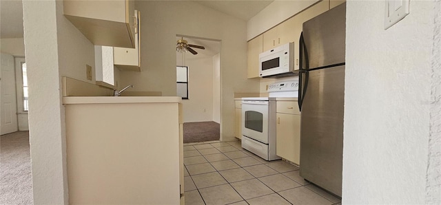 kitchen featuring vaulted ceiling, light tile patterned floors, ceiling fan, white appliances, and cream cabinetry