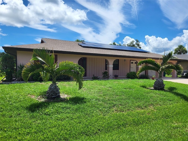 ranch-style house featuring a front lawn, solar panels, and covered porch