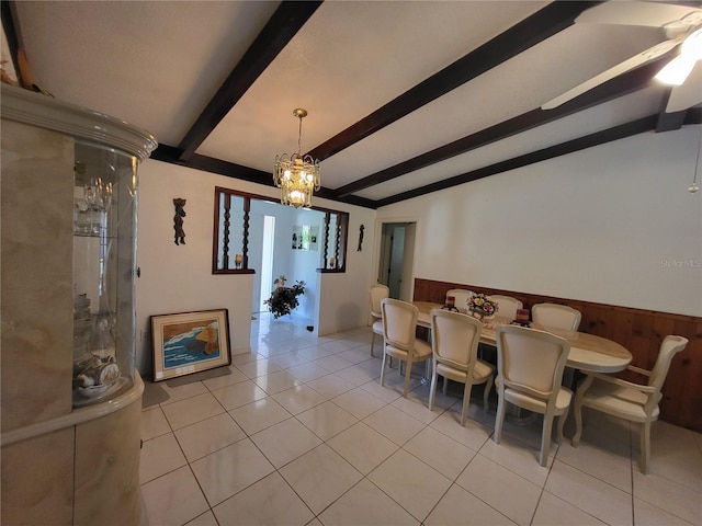 dining room featuring an inviting chandelier, light tile patterned floors, wooden walls, and lofted ceiling with beams