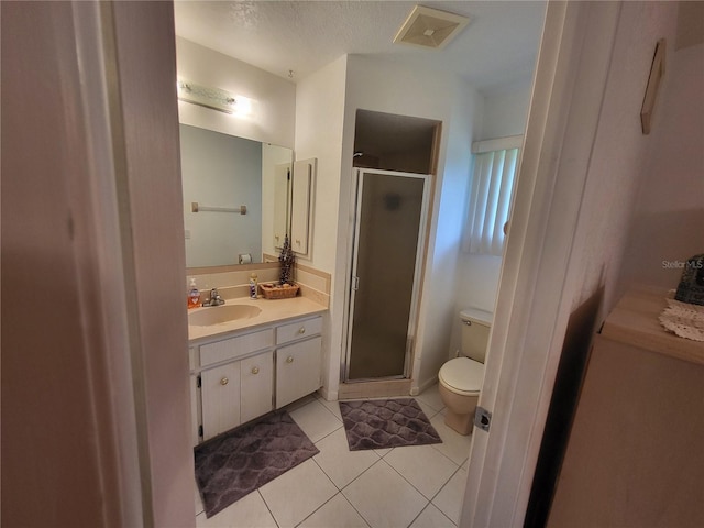 bathroom with toilet, vanity, tile patterned flooring, and a shower with shower door