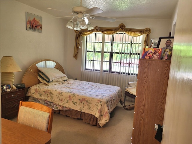 carpeted bedroom featuring ceiling fan and a textured ceiling