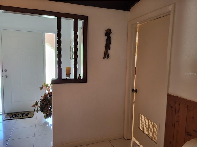 foyer with light tile patterned floors and wood walls