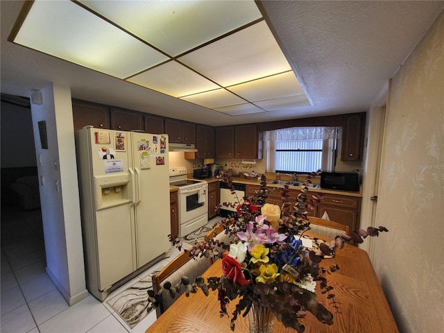 kitchen featuring sink, white appliances, dark brown cabinetry, and light tile patterned flooring