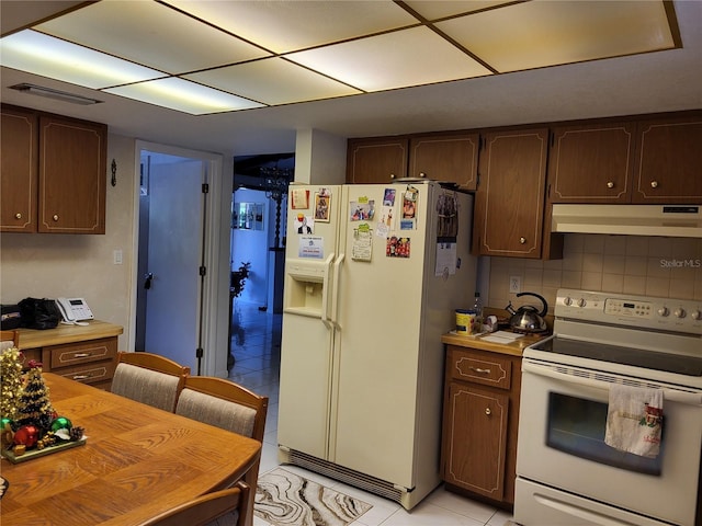 kitchen featuring light tile patterned floors, decorative backsplash, dark brown cabinets, and white appliances