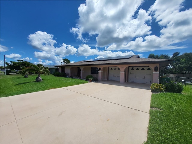 ranch-style home with a front yard, solar panels, and a garage