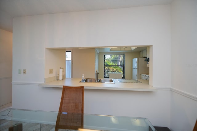 kitchen with kitchen peninsula, sink, and white fridge