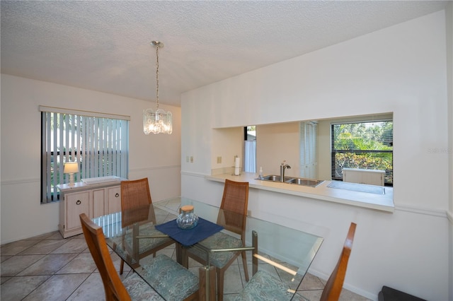 dining area featuring tile patterned flooring, a chandelier, sink, and a textured ceiling