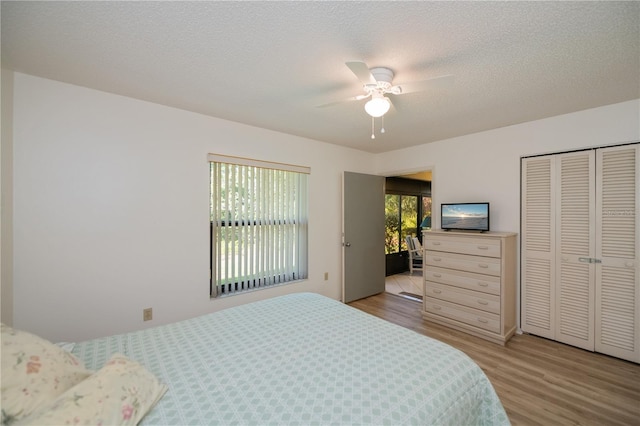 bedroom with a textured ceiling, a closet, ceiling fan, and light hardwood / wood-style floors