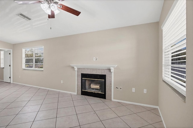 unfurnished living room featuring ceiling fan, light tile patterned floors, and a fireplace