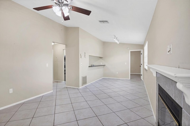 unfurnished living room featuring ceiling fan, light tile patterned floors, lofted ceiling, and a tiled fireplace